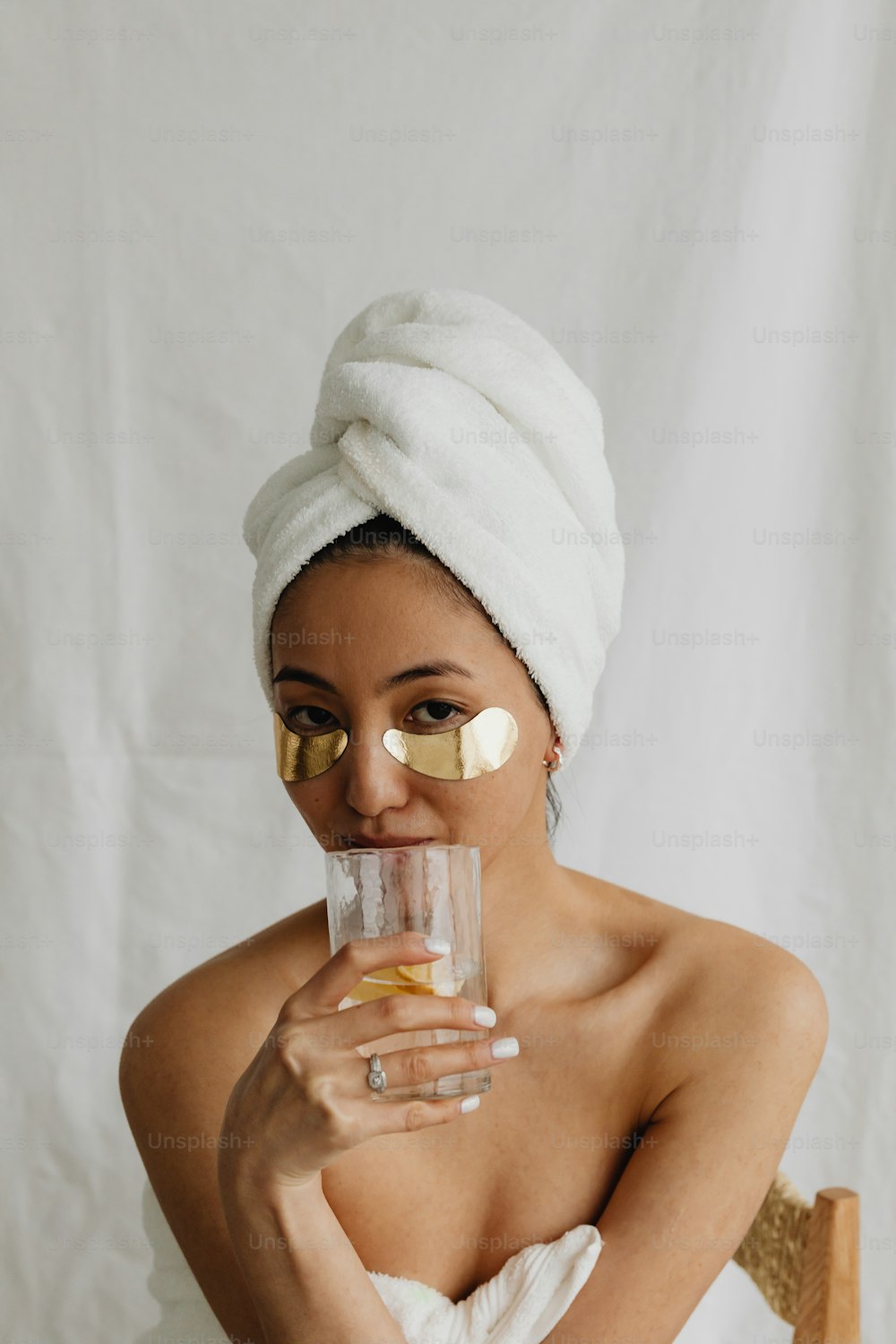 a woman with a towel on her head holding a glass