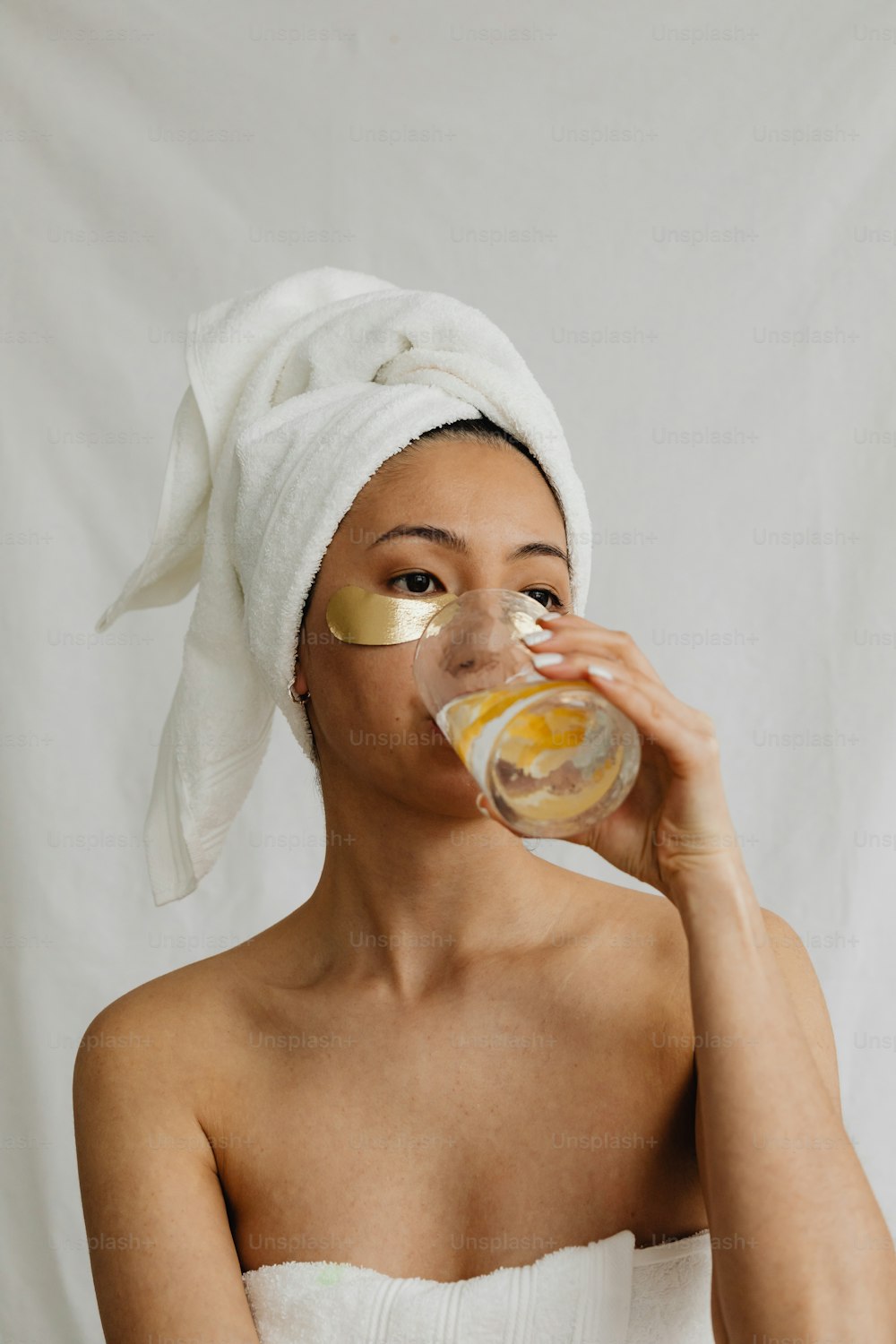 uma mulher com uma toalha na cabeça bebendo de um copo