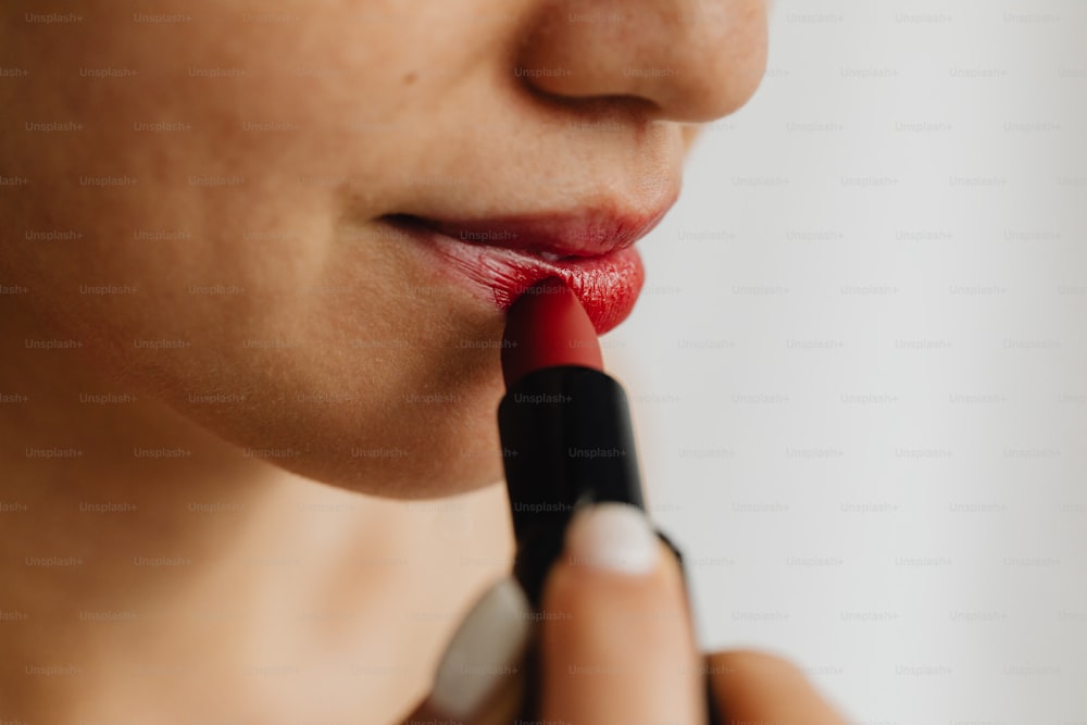 Une femme met du rouge à lèvres sur ses lèvres