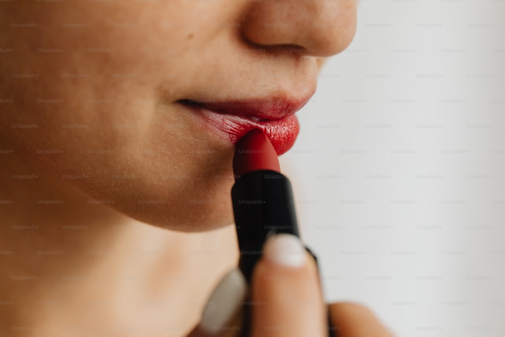 a woman is putting lipstick on her lips