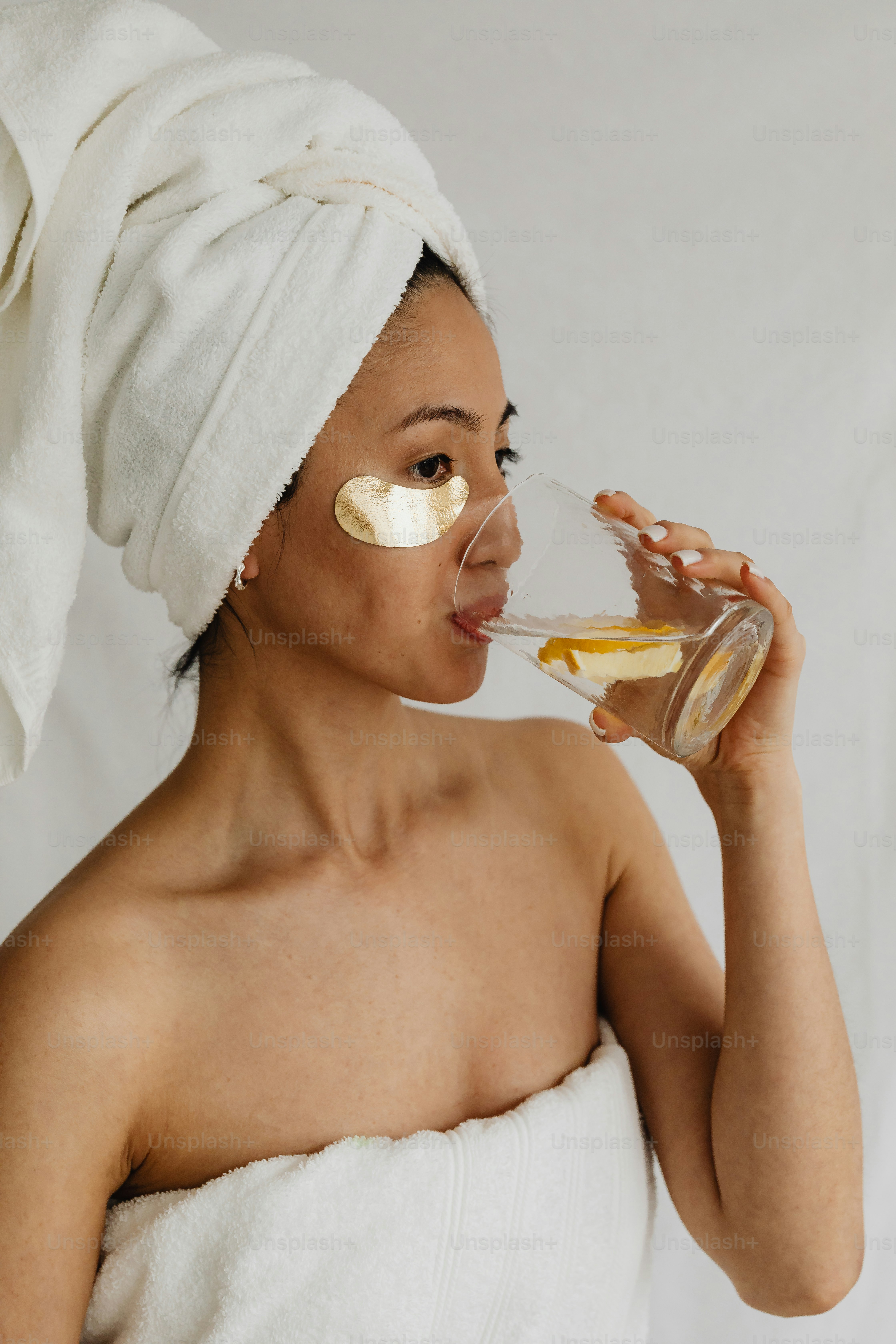 頭にタオルをかぶった女性がグラスから飲む