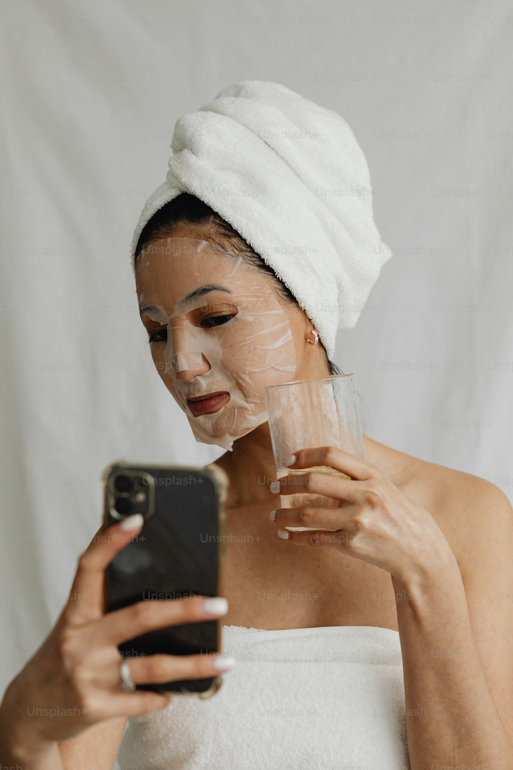 a woman with a towel on her head holding a cell phone