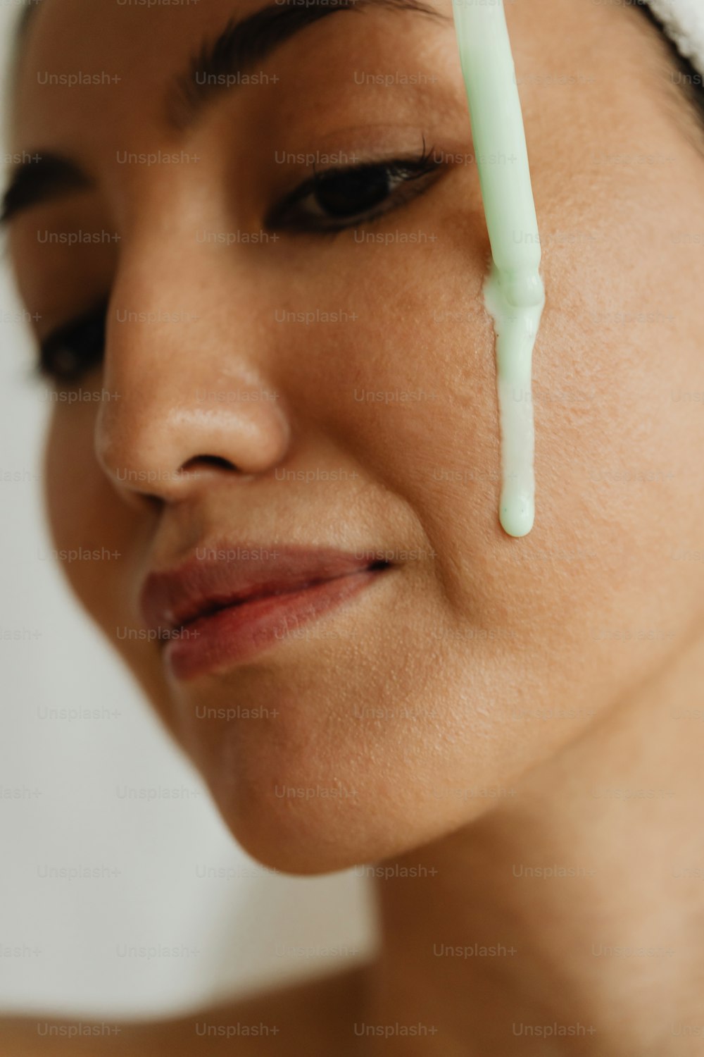 Una donna con un asciugamano in testa ha una sostanza verde sulla fronte