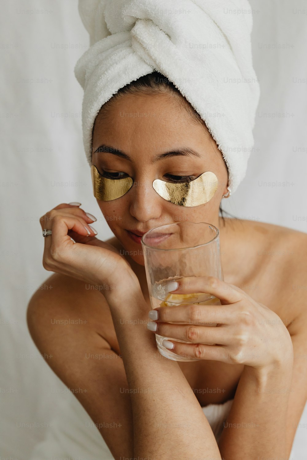 a woman with a towel on her head holding a glass of water