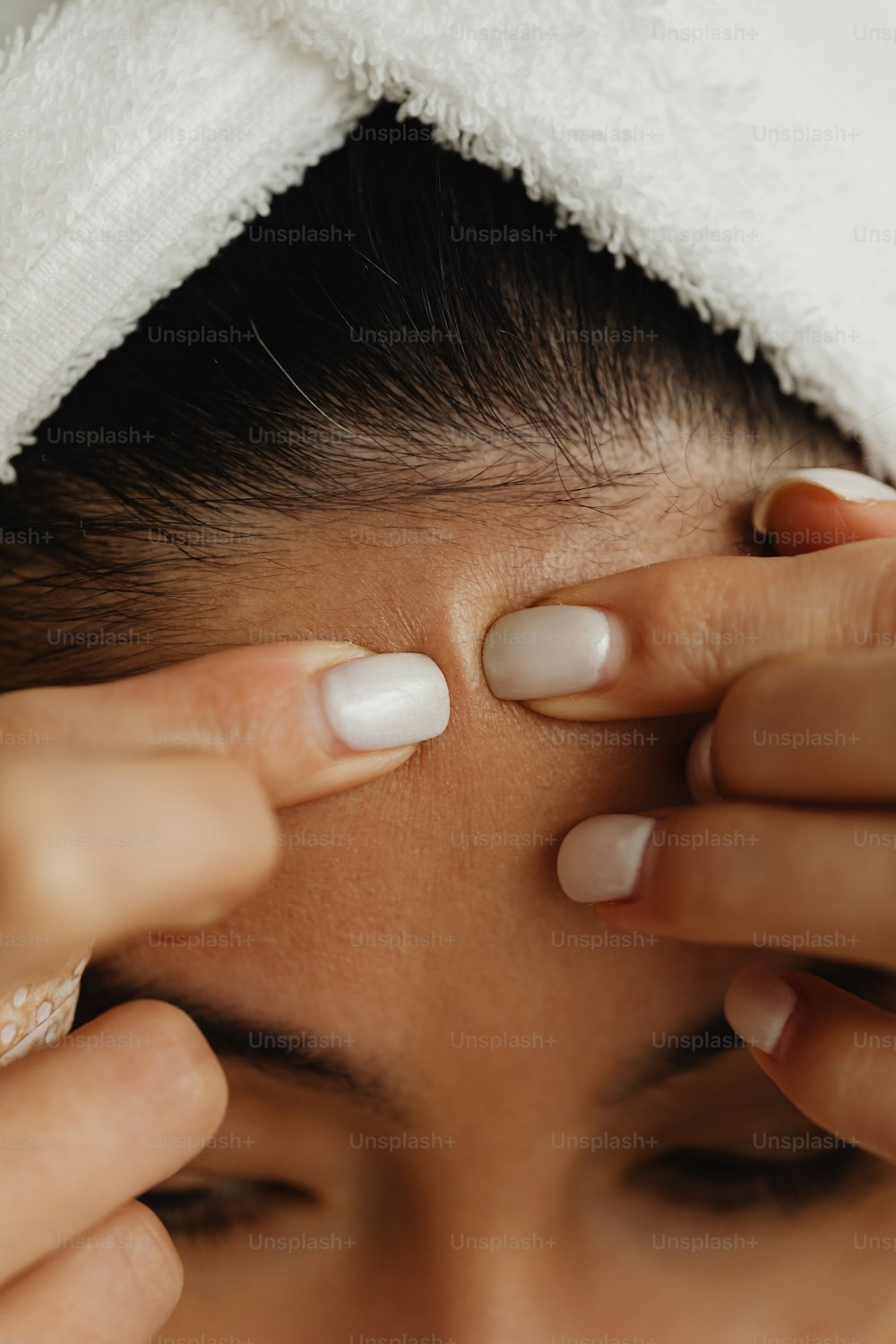 a woman getting her nails done with a towel on her head