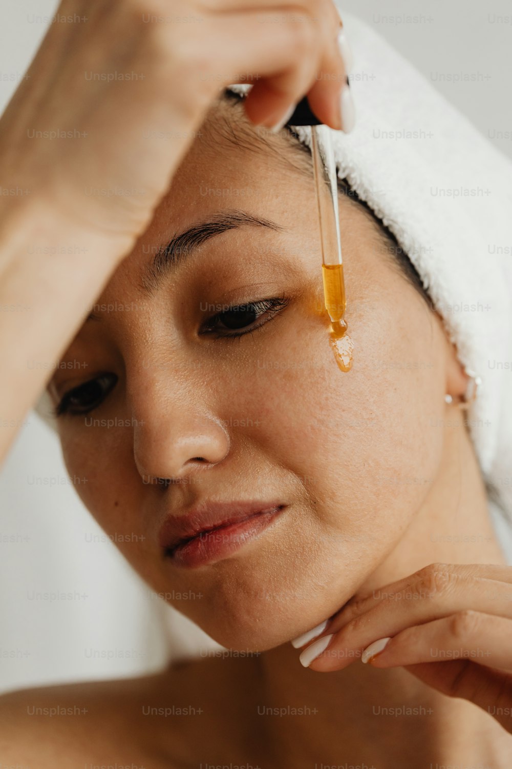 a woman with a towel on her head and a drop of liquid on her forehead