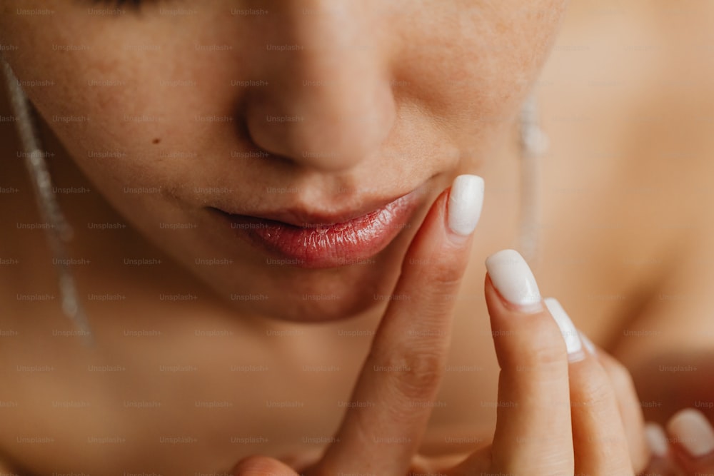 a close up of a woman with a white manicure