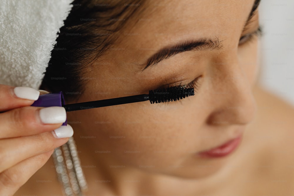 a woman is putting mascara on her face