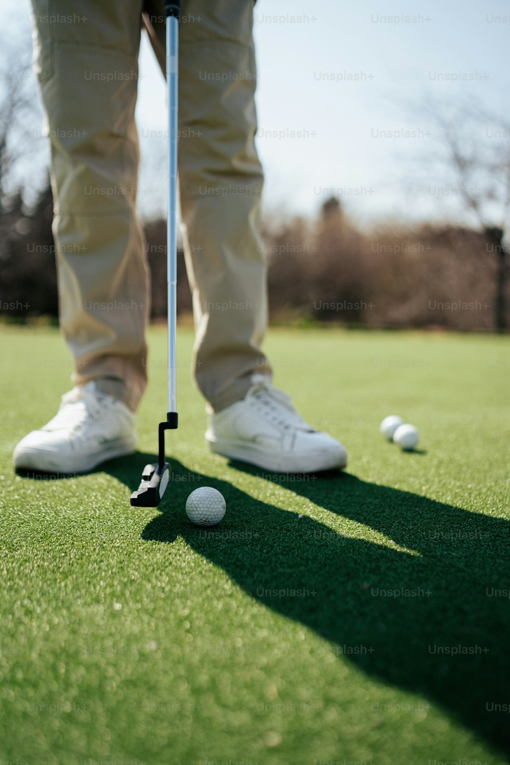 um homem em pé em cima de um campo verde ao lado de uma bola de golfe