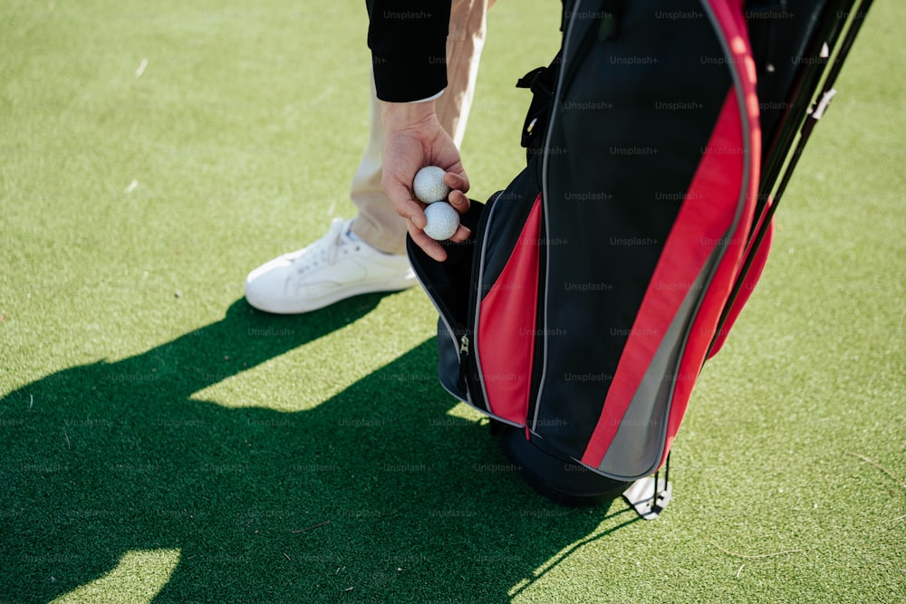 a man holding a golf ball and a golf bag