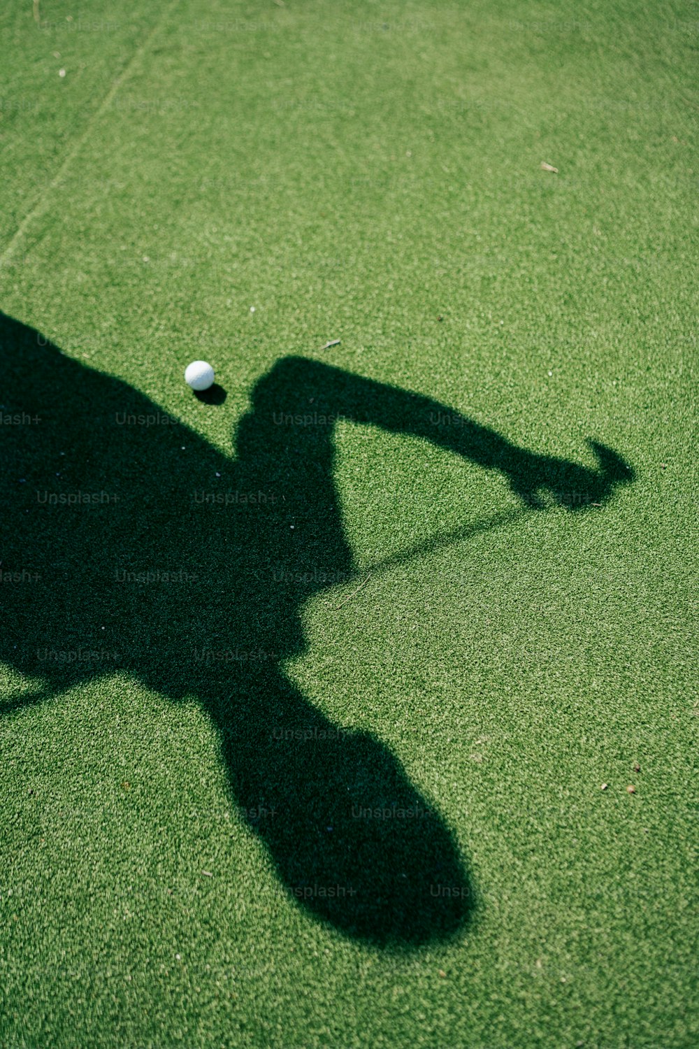 uma sombra de uma pessoa batendo em uma bola de tênis