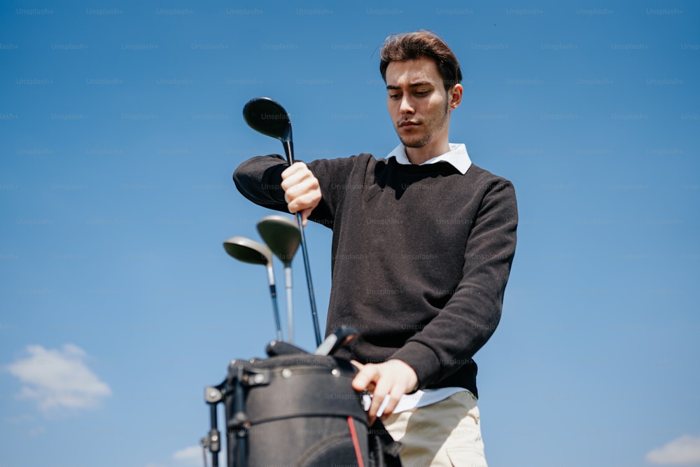 a man holding a golf club and a bag of golf clubs
