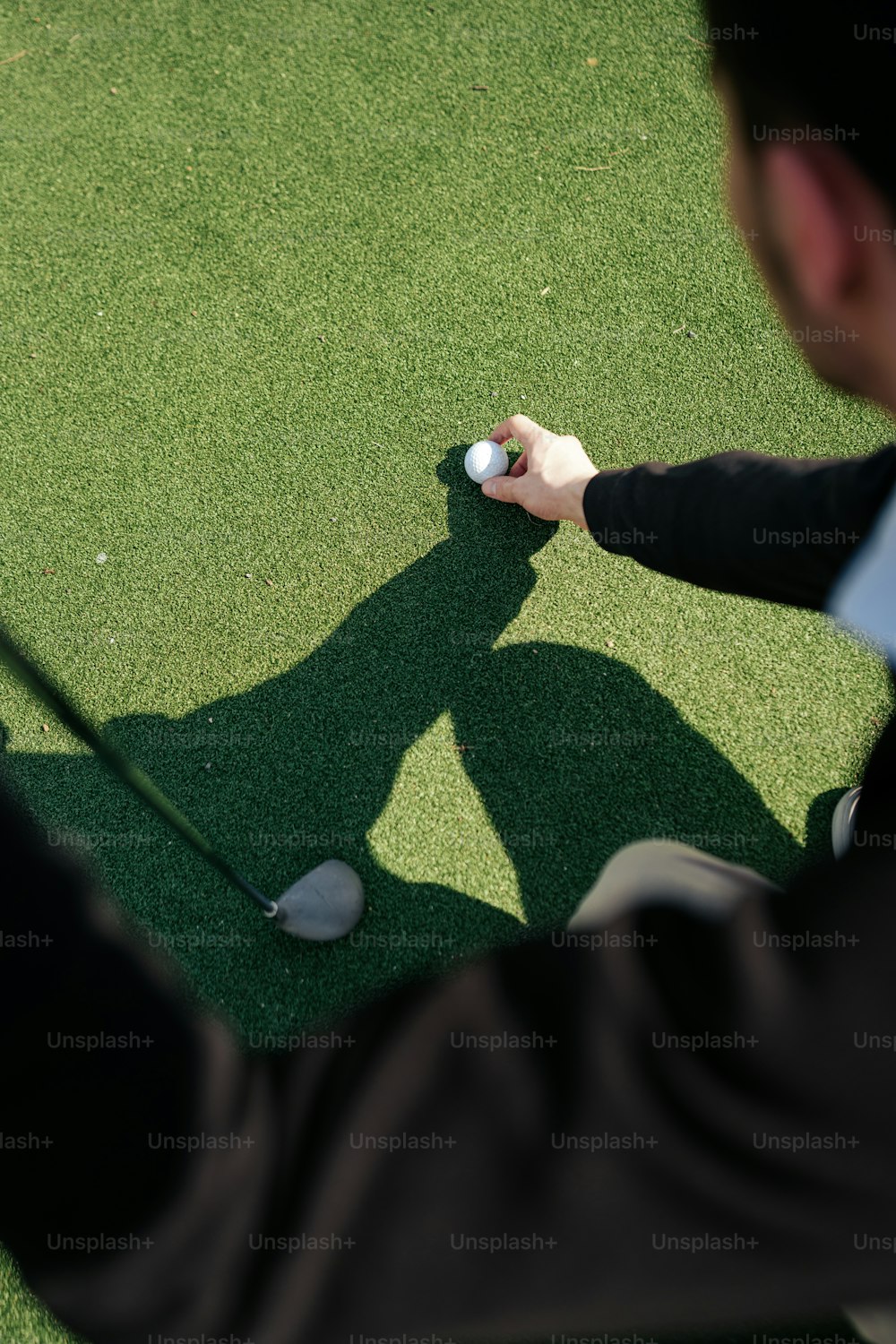 a man holding a golf club on top of a green field