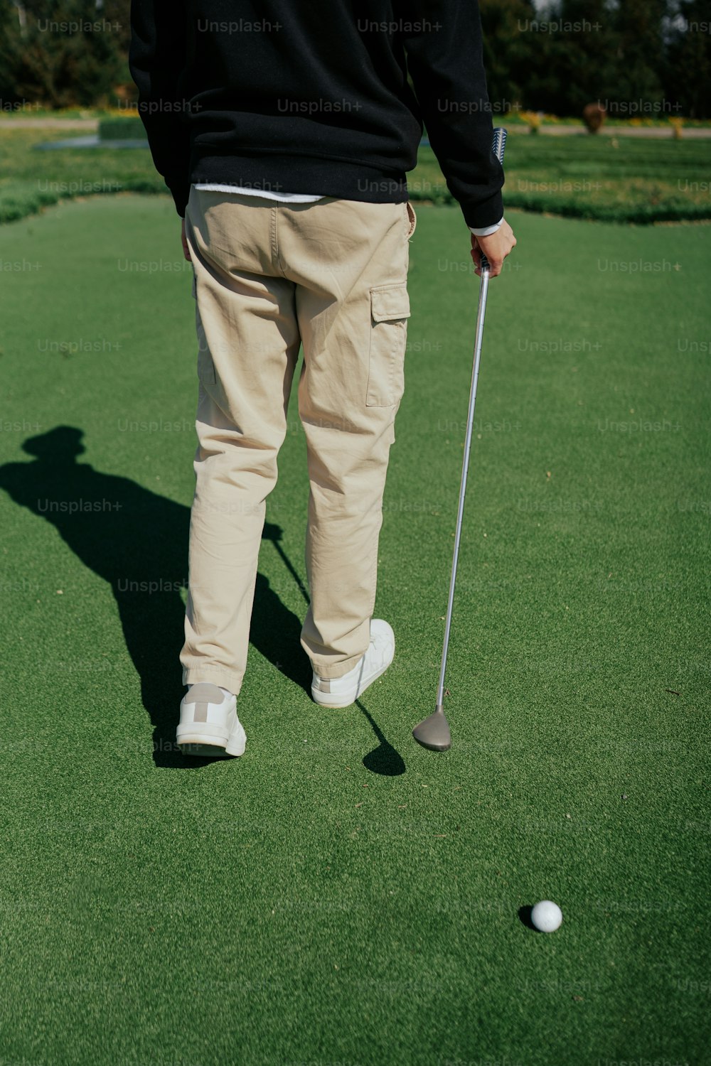 a man standing on top of a green putting a golf ball