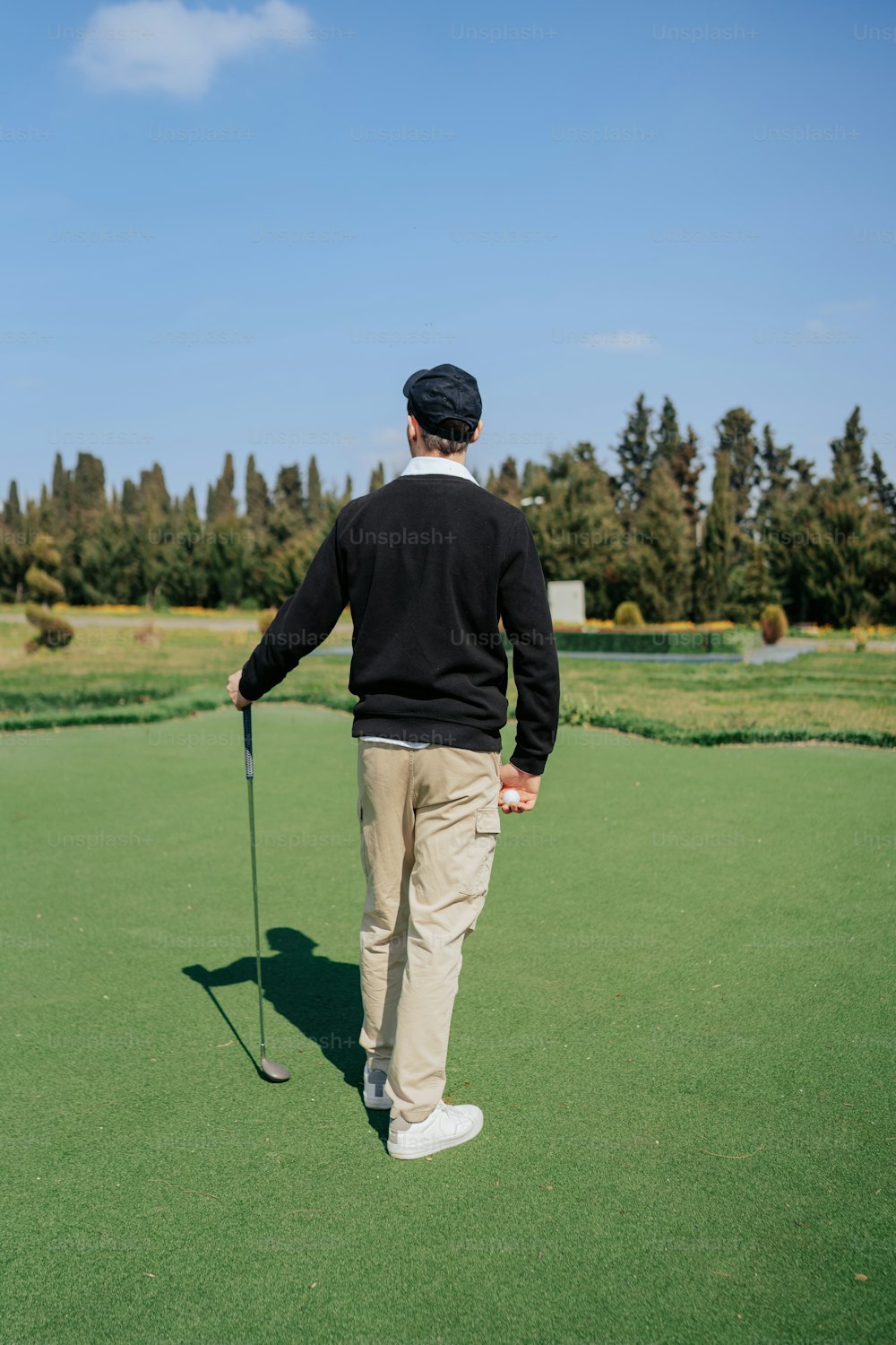 a man standing on top of a green field holding a golf club