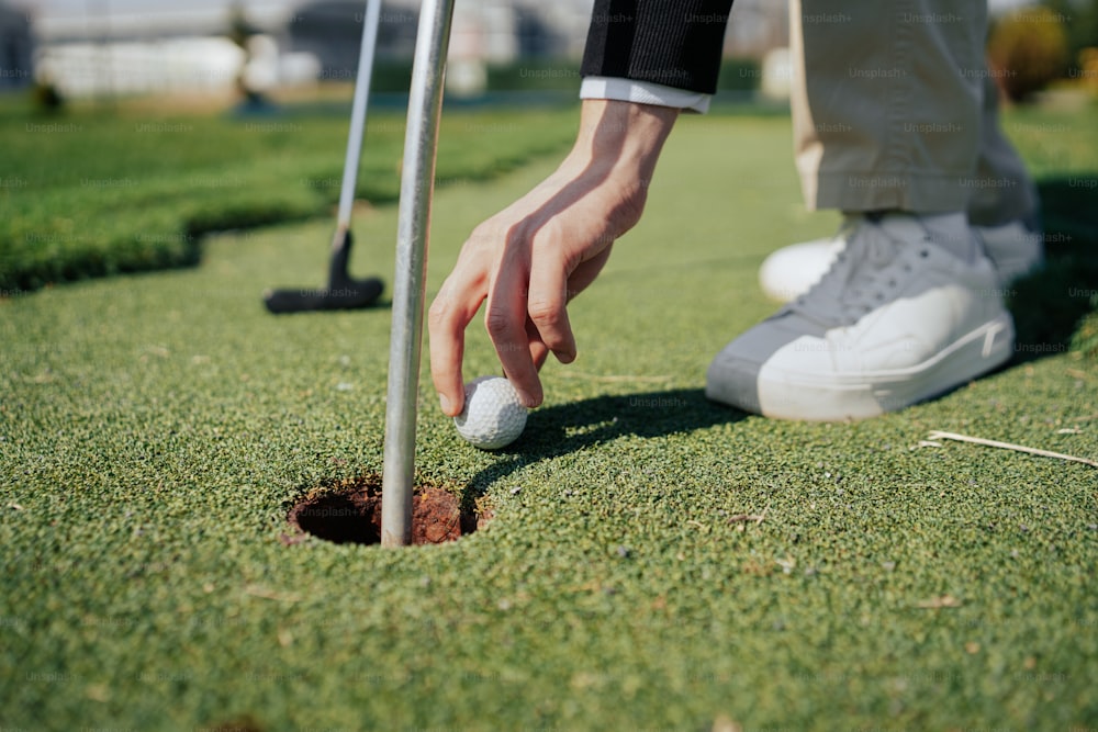 a person putting a golf ball into a hole