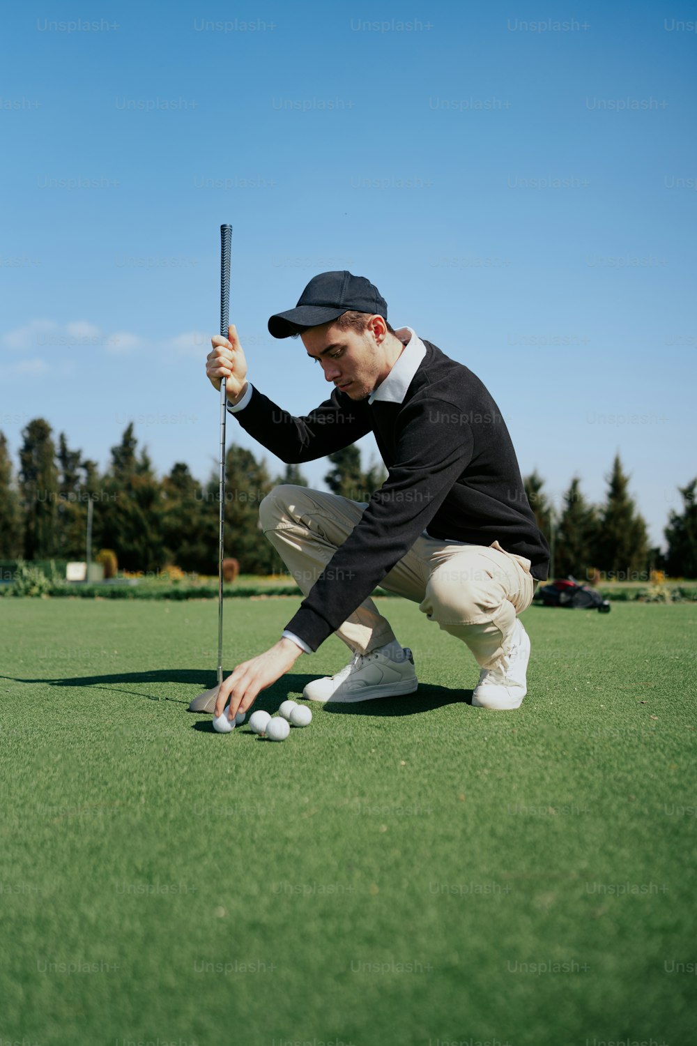 um homem ajoelhado para colocar uma bola de golfe no green