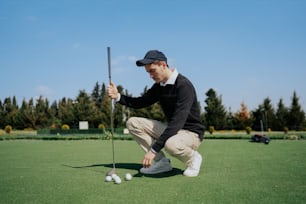a man kneeling down to put a golf ball in the hole