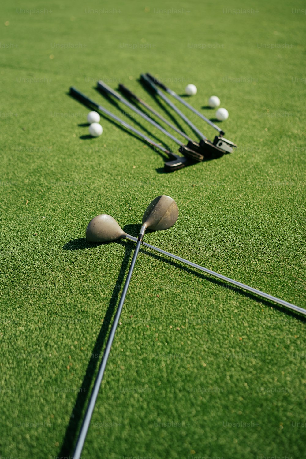 Un grupo de palos de golf y pelotas tendidas en el césped