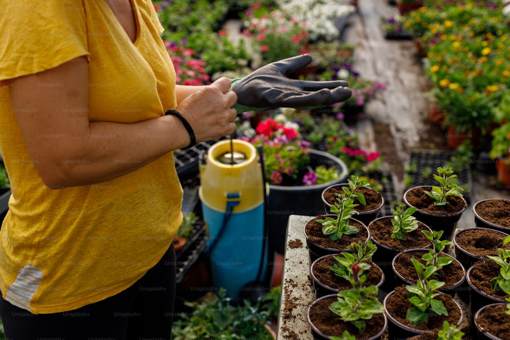 a woman in a yellow shirt holding a pair of gardening gloves