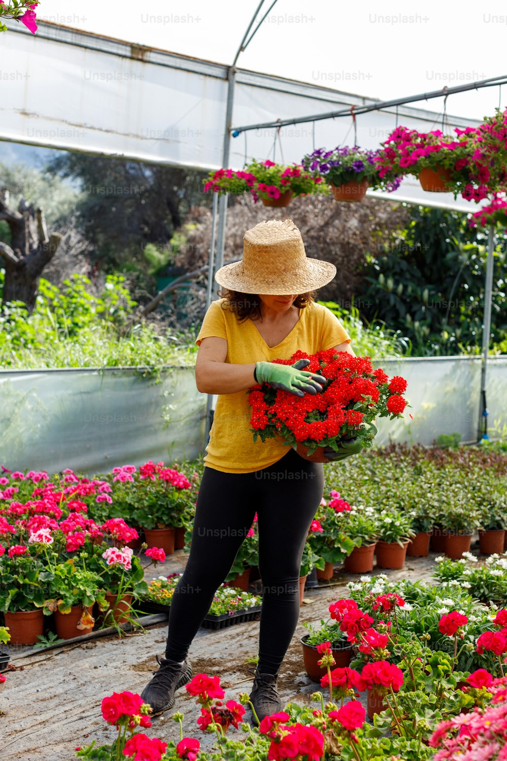 Eine Frau in gelbem Hemd und Hut, die einen Blumenstrauß hält