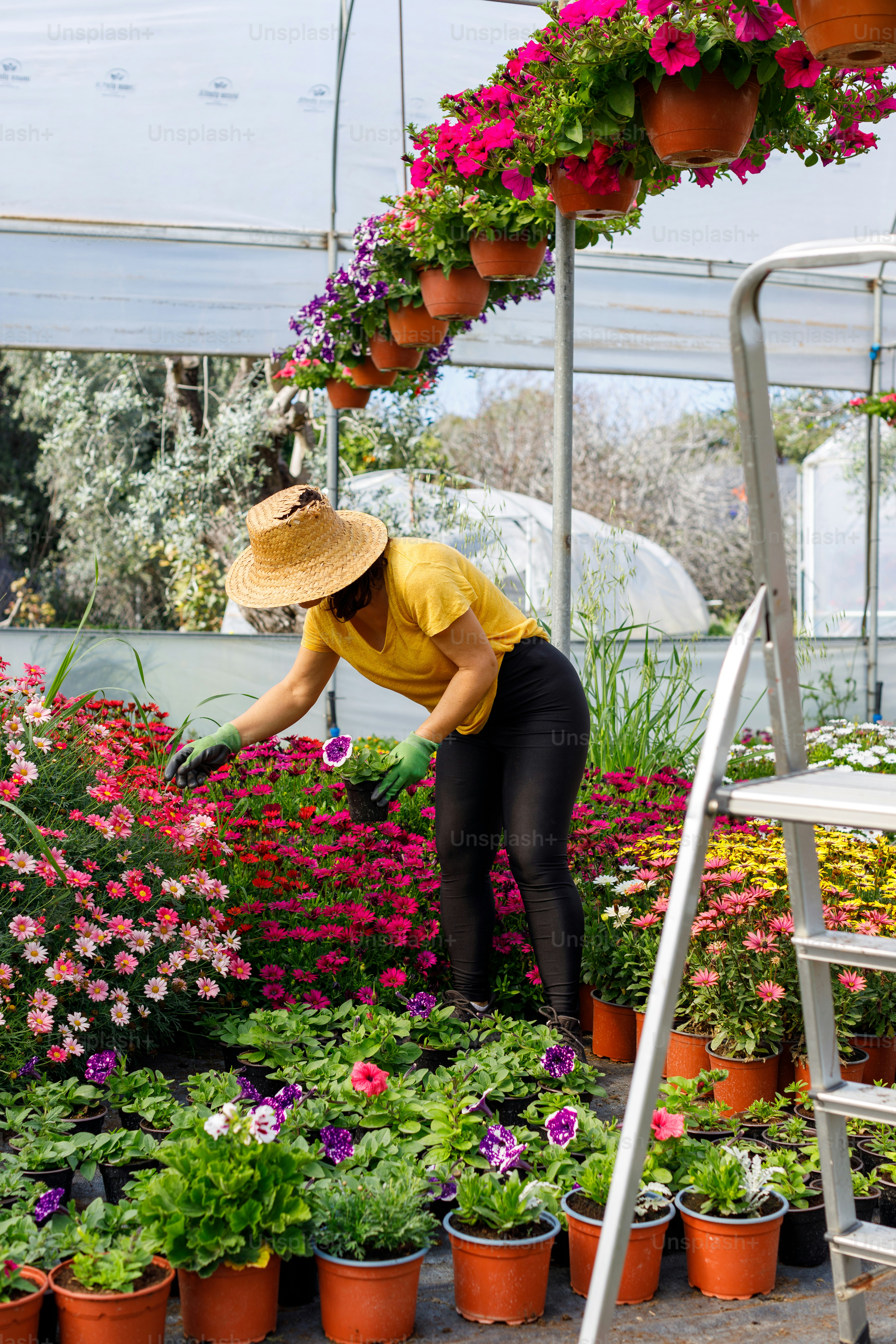 Una donna in una camicia gialla e cappello di paglia tendente ai fiori