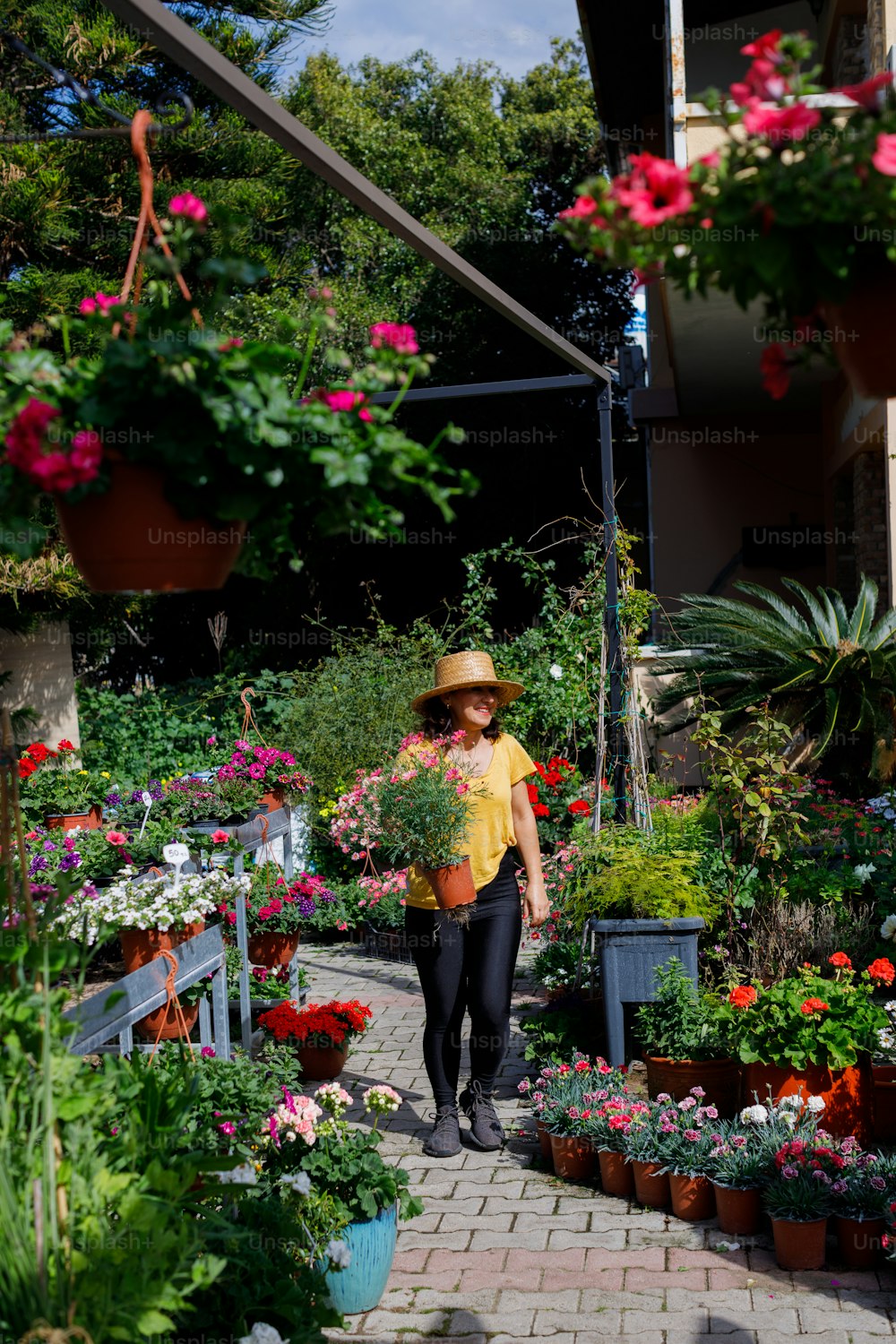 a woman walking through a garden filled with lots of flowers