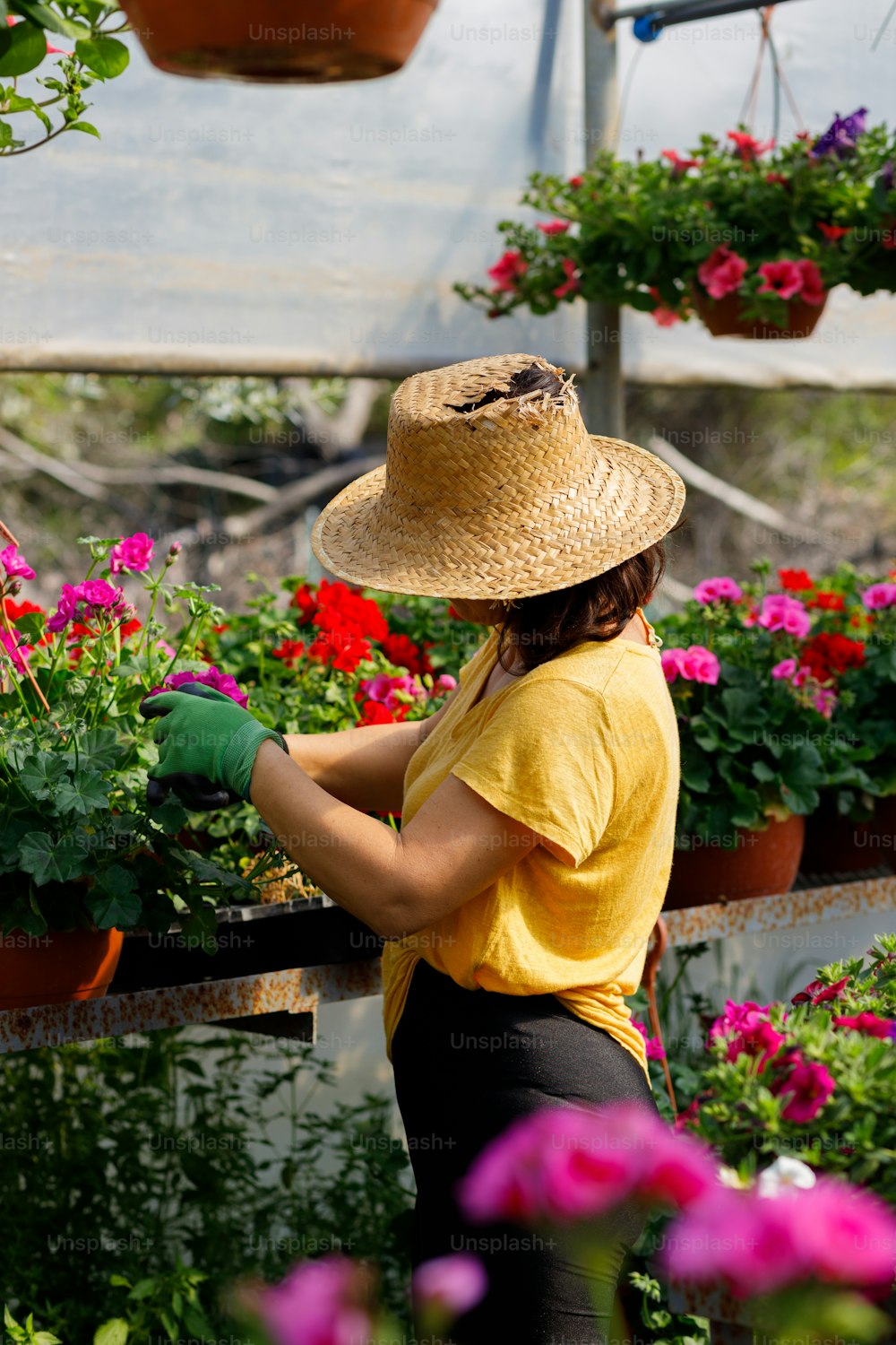 a woman wearing a straw hat and gardening gloves