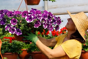 a woman in a yellow shirt and hat holding a potted plant