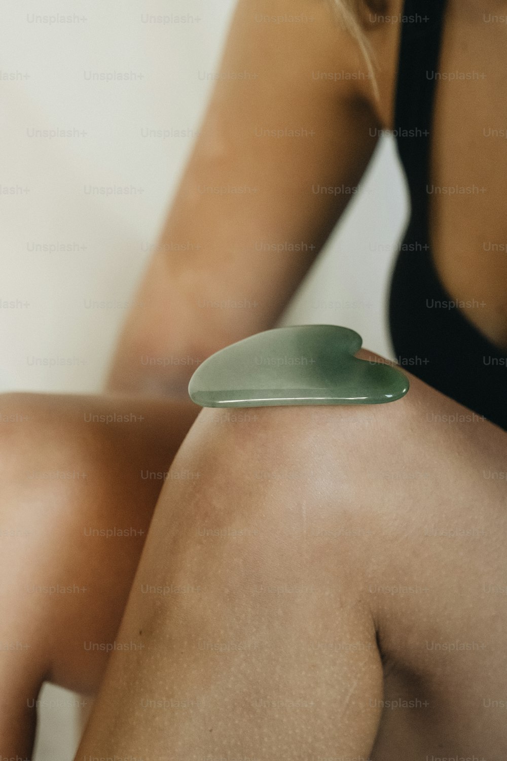 a woman sitting on the ground with a green object on her arm