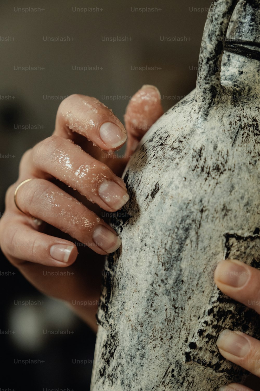 a woman's hands holding a vase with dirt on it