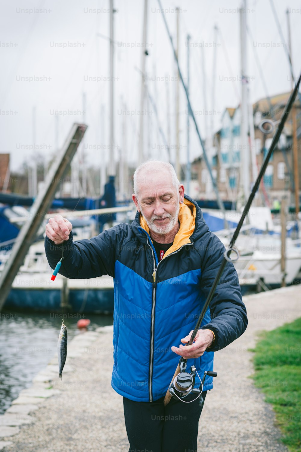 a man holding a fish while standing next to a body of water