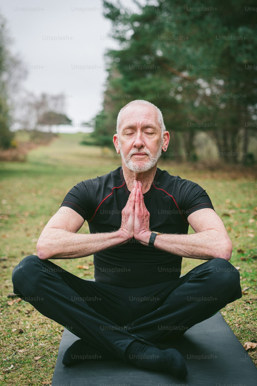 Ein Mann in schwarzem Hemd und schwarzer Hose beim Yoga