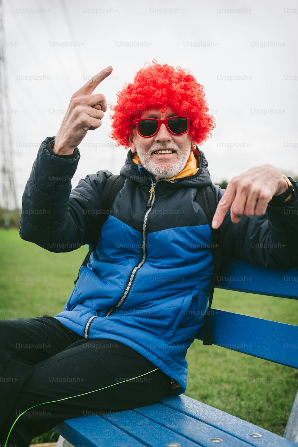 a man with a red wig sitting on a blue bench