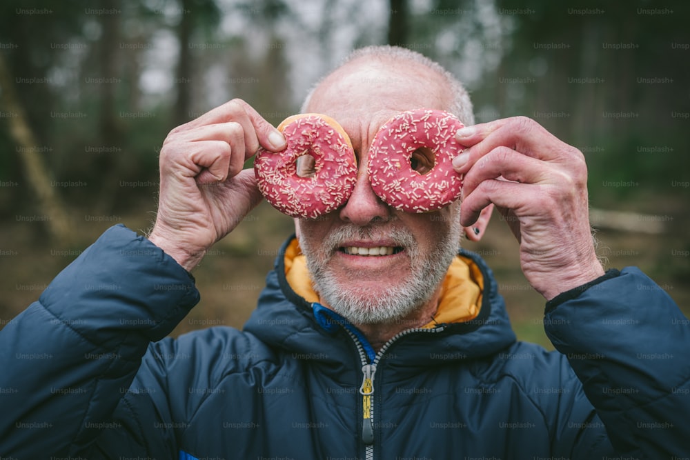 a man holding two doughnuts up to his eyes