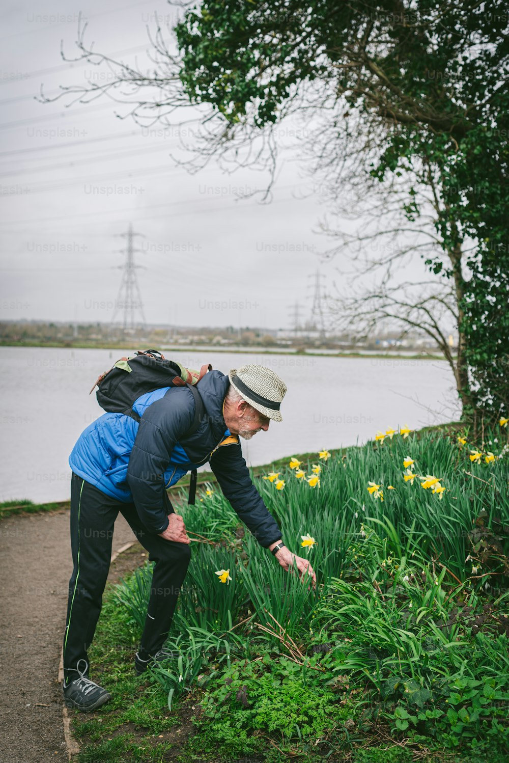 a man with a backpack picking up some flowers