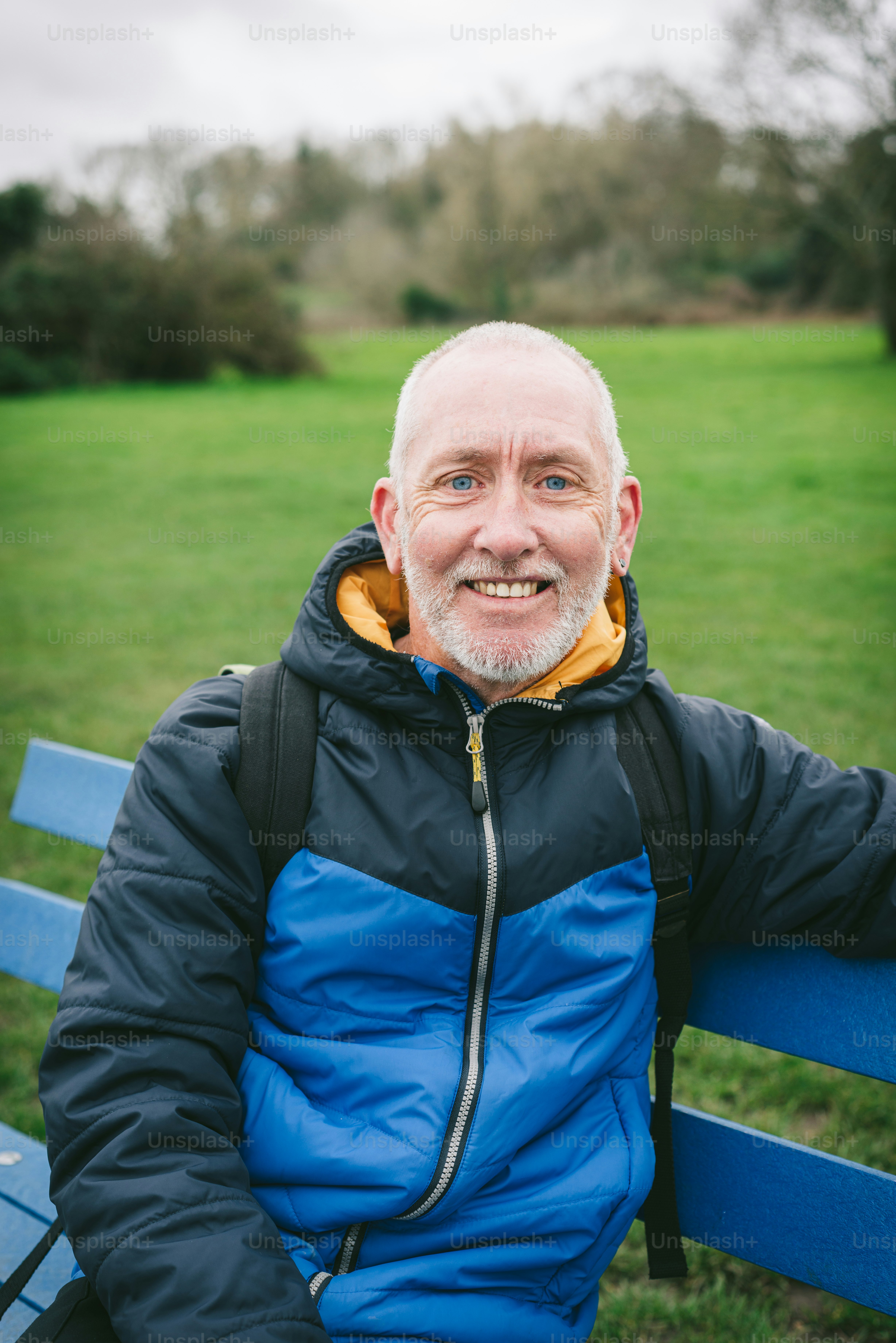 a man sitting on a blue bench in a park