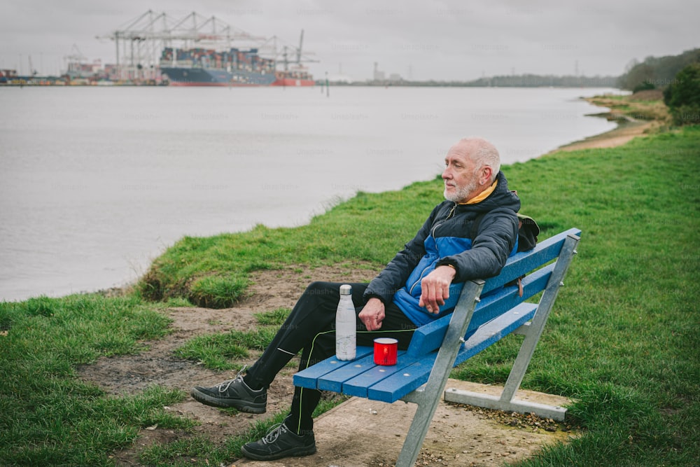 a man sitting on a bench next to a body of water