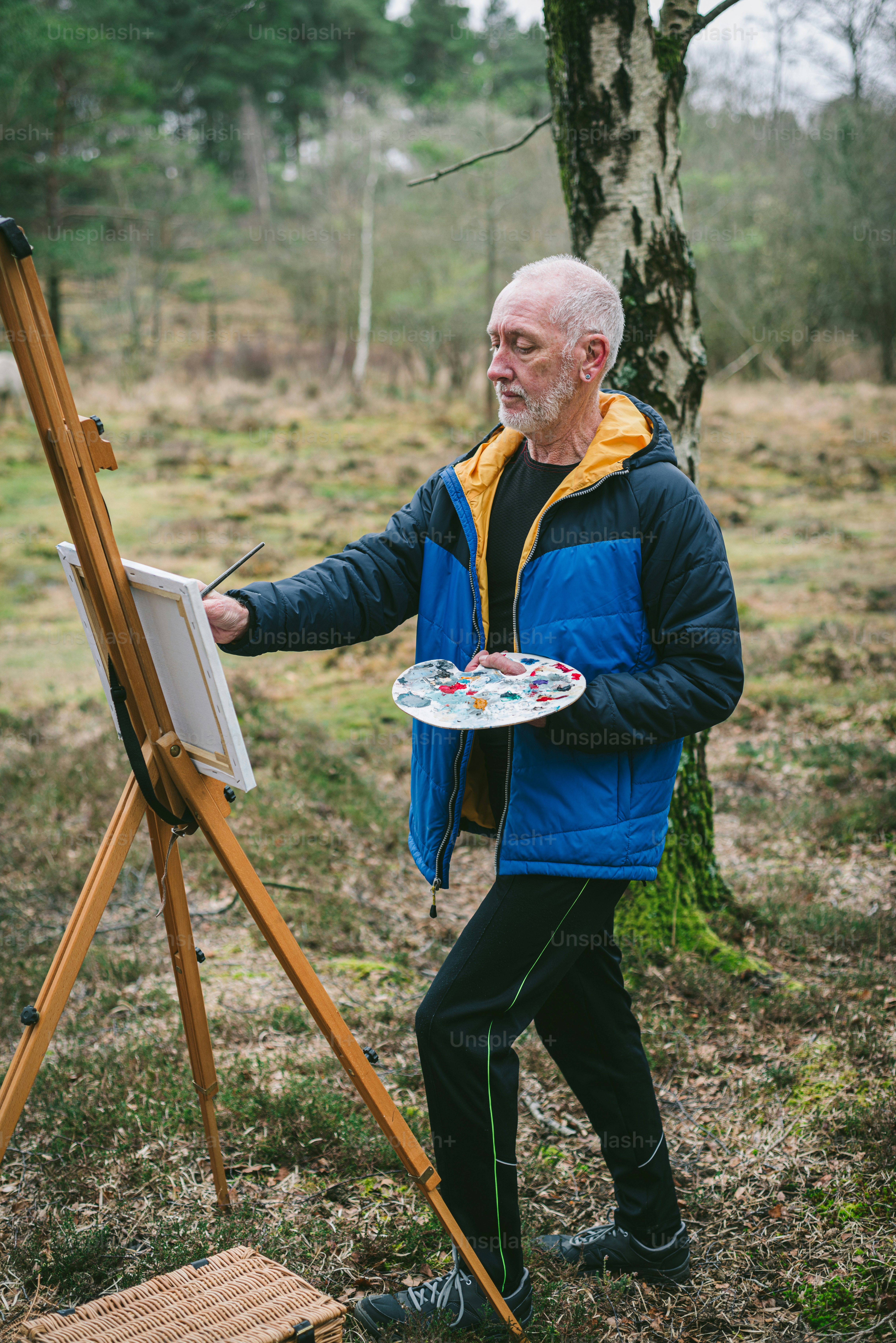 a man standing next to a easel holding a painting