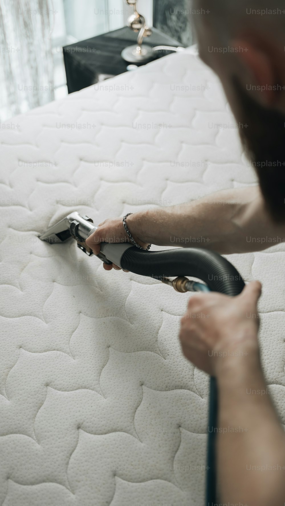 Un uomo sta pulendo un materasso con un aspirapolvere