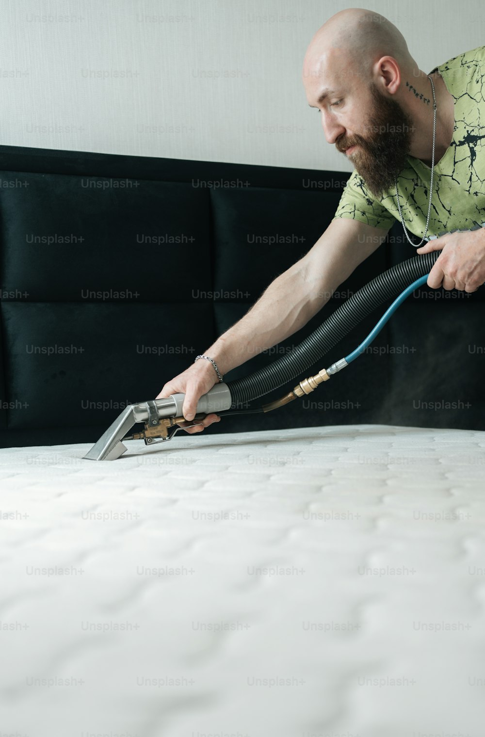 a man vacuuming a mattress with a hose