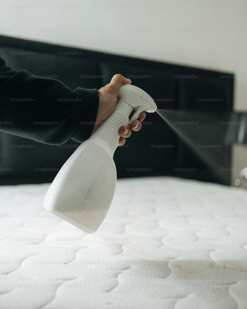 Una persona que usa una botella de spray para limpiar un colchón