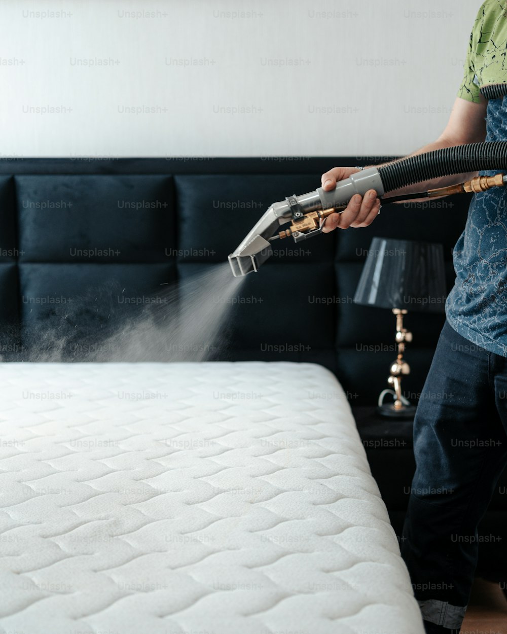 Un hombre aspirando un colchón con un limpiador a vapor