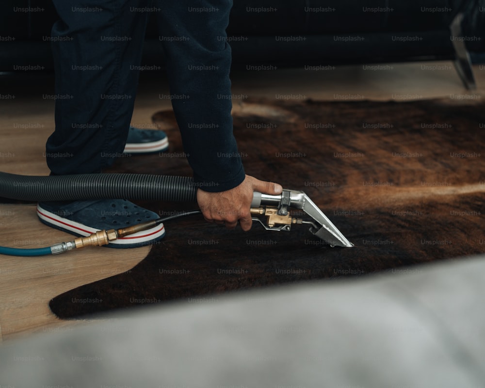 a person vacuuming a rug with a vacuum cleaner