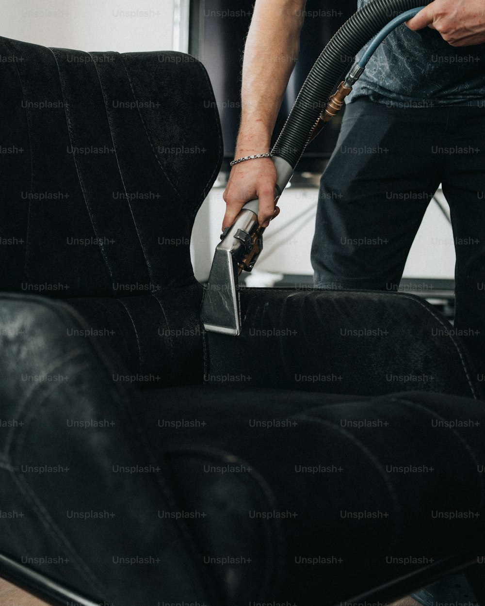 a man using a vacuum to clean a black couch