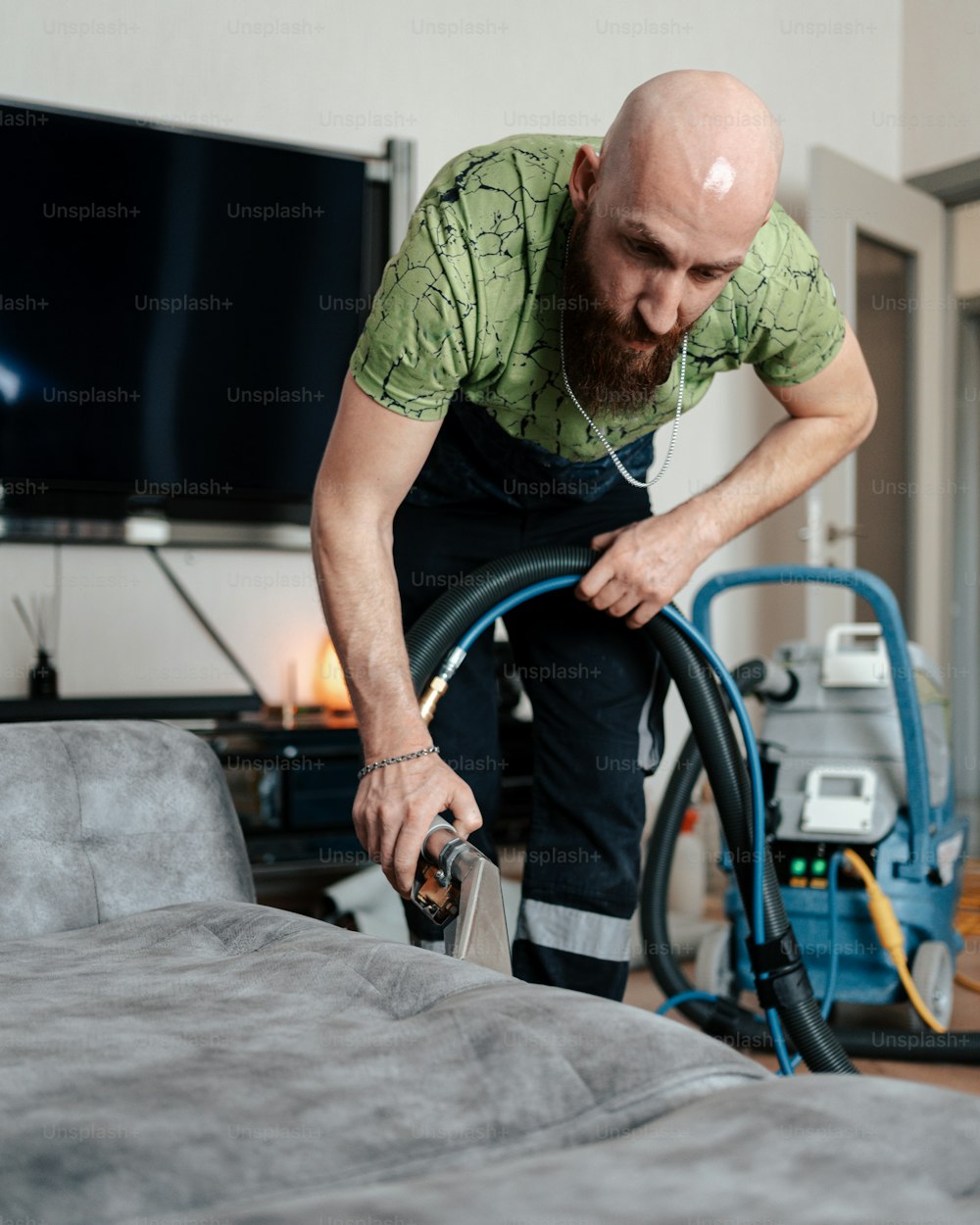 a man in a green shirt vacuuming a bed