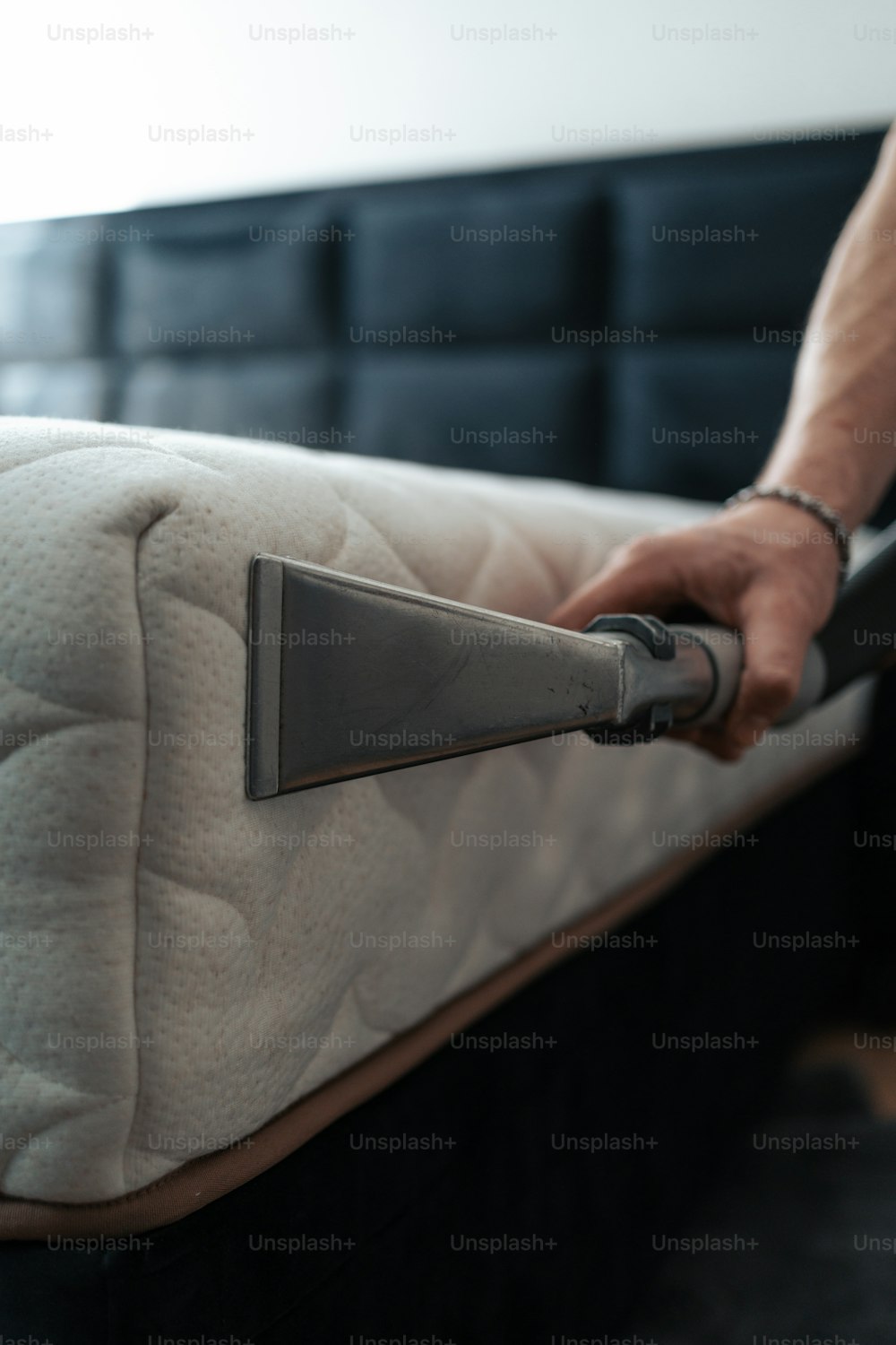 a person vacuuming a mattress with a vacuum cleaner