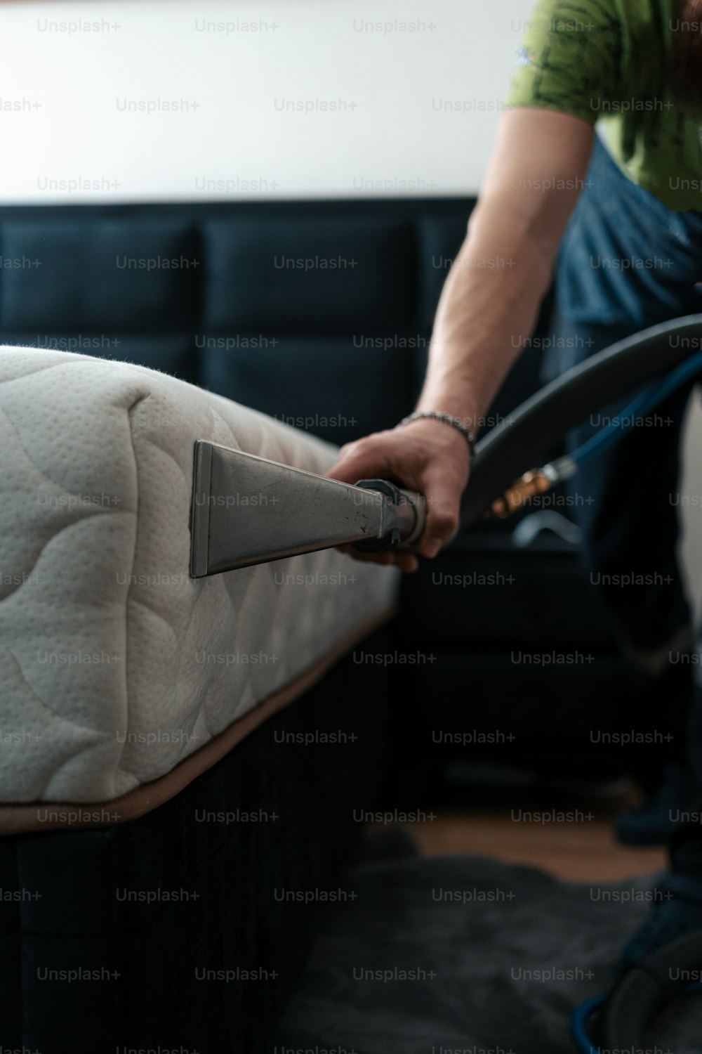 Ein Mann reinigt eine Matratze mit einem Staubsauger