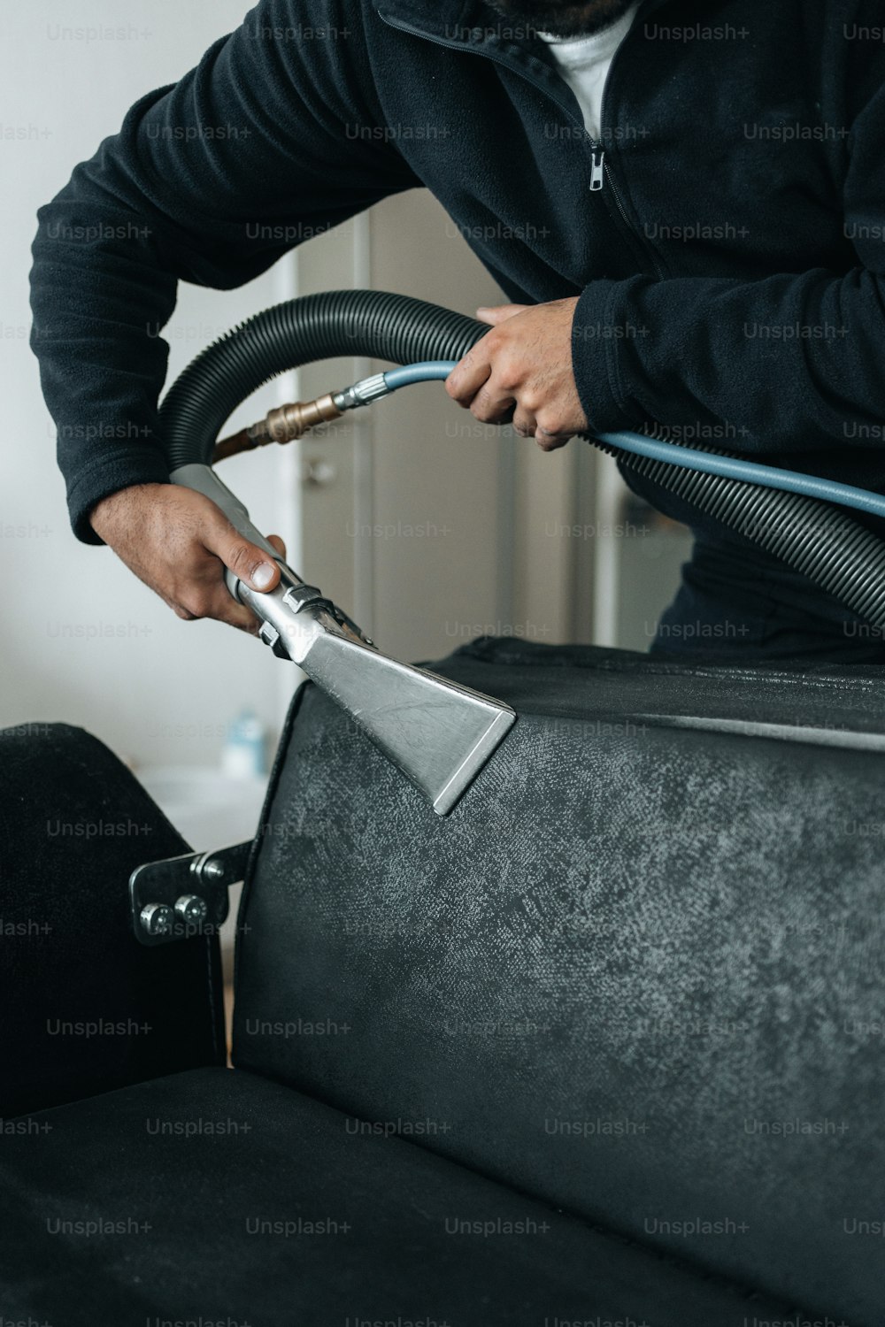 a man is using a vacuum to clean a couch