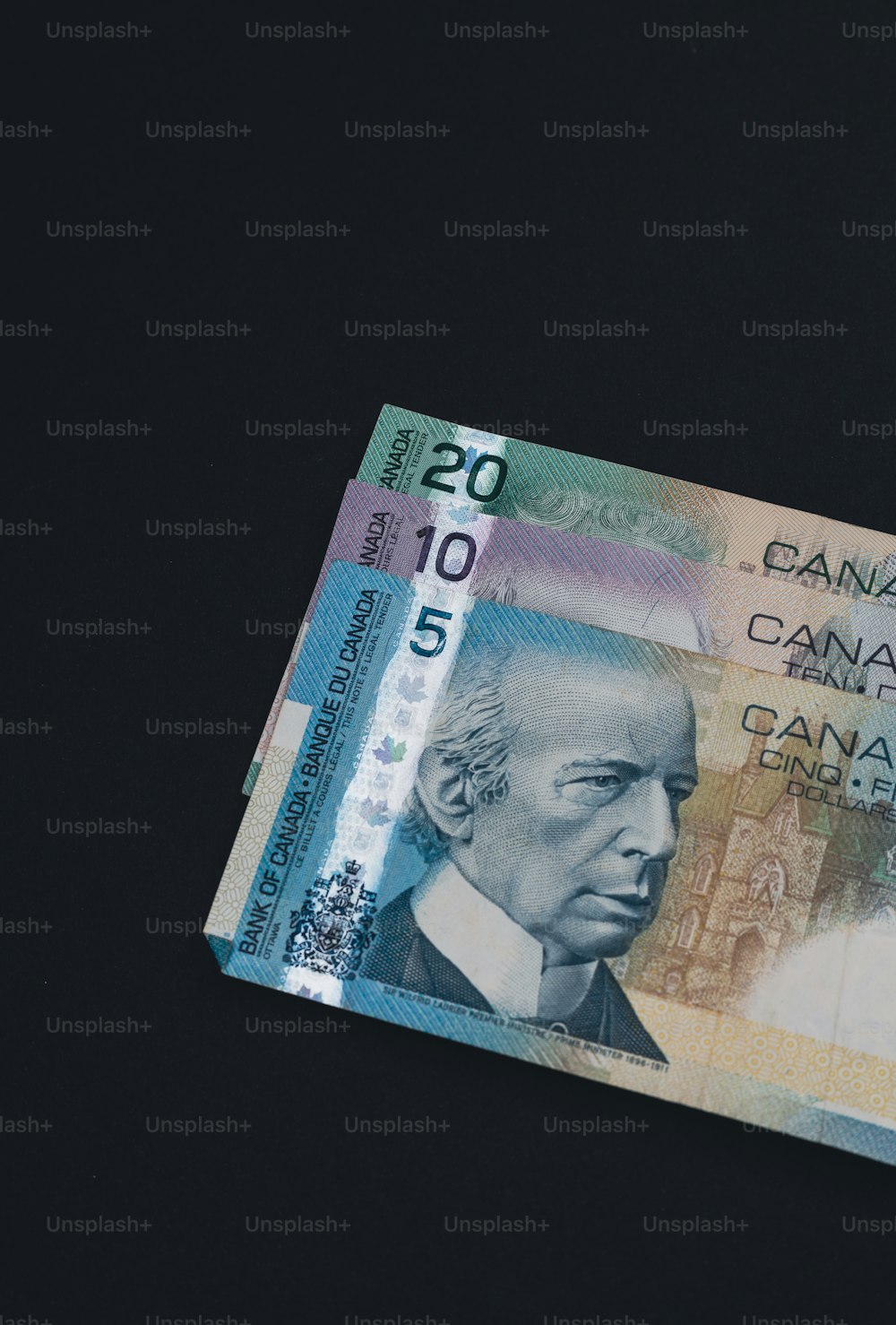 a canadian twenty dollar bill on a black background